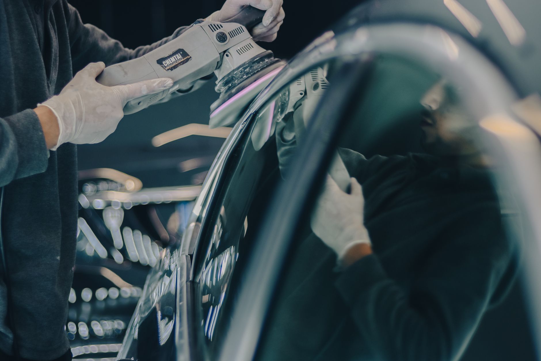 Technician using a polishing machine to prep a car's paint before a coating