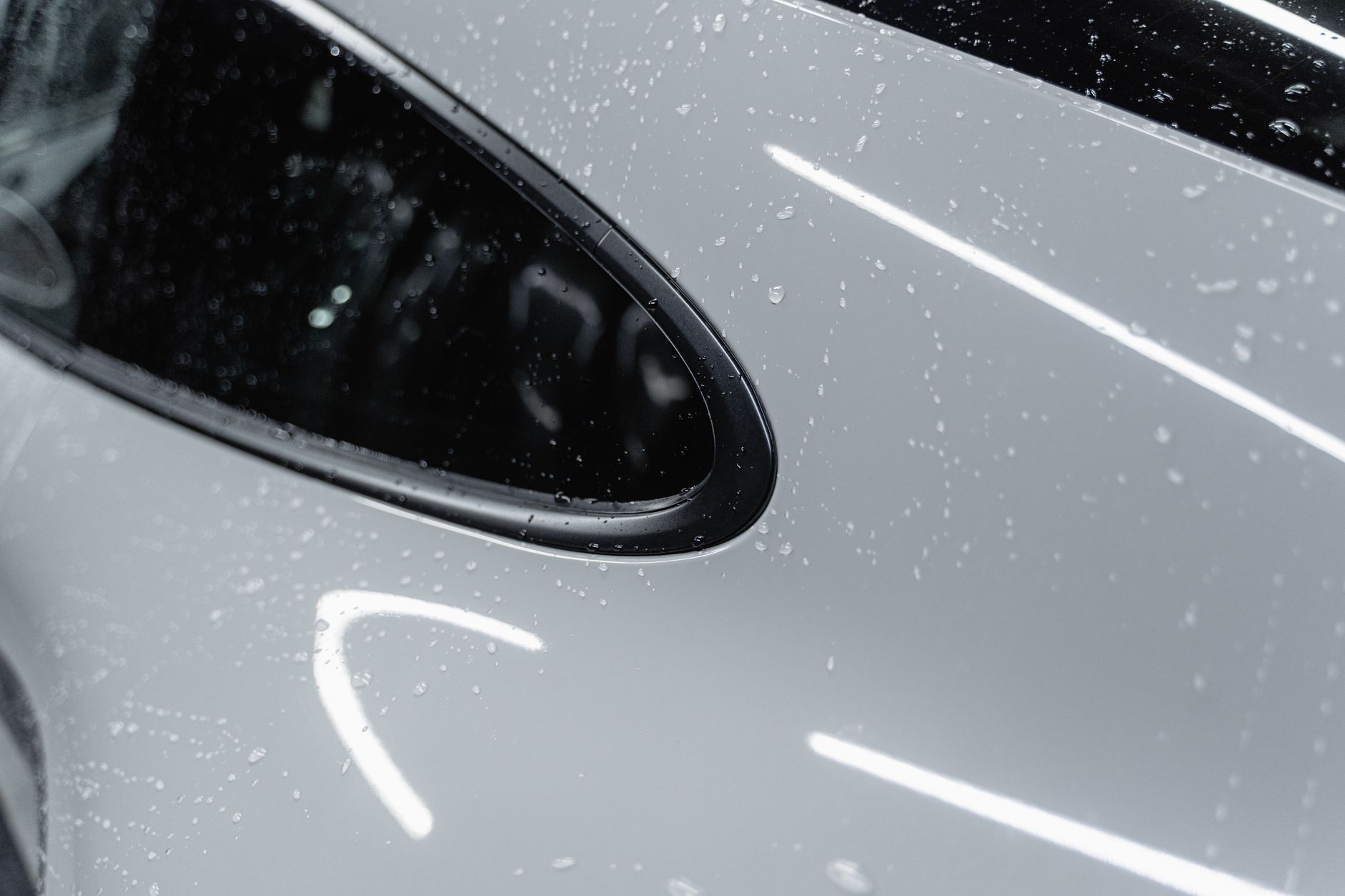 Close-up of water beading on a white car's hood after a ceramic coating